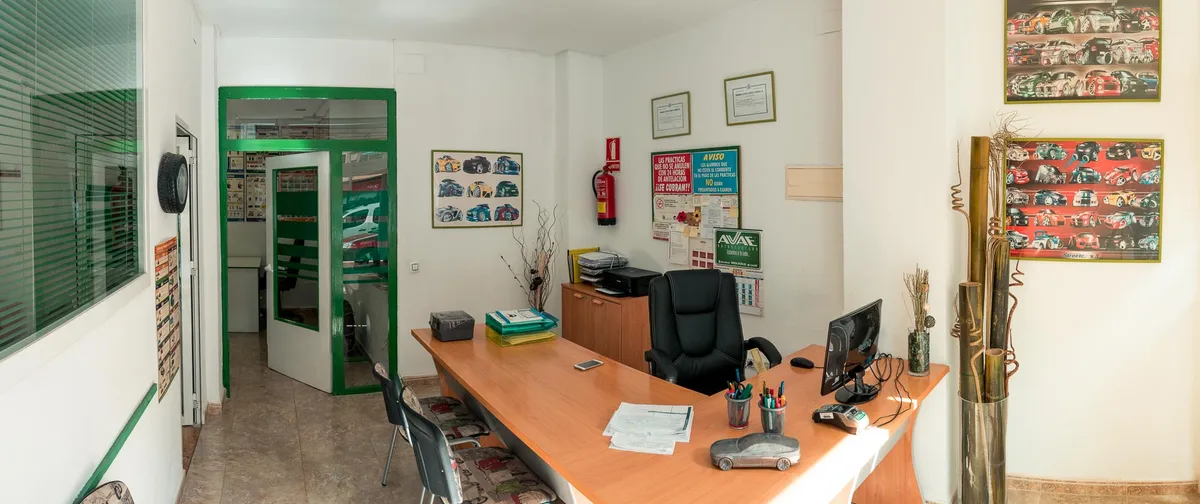 Recepción de la autoescuela, con la puerta verde del despacho al fondo